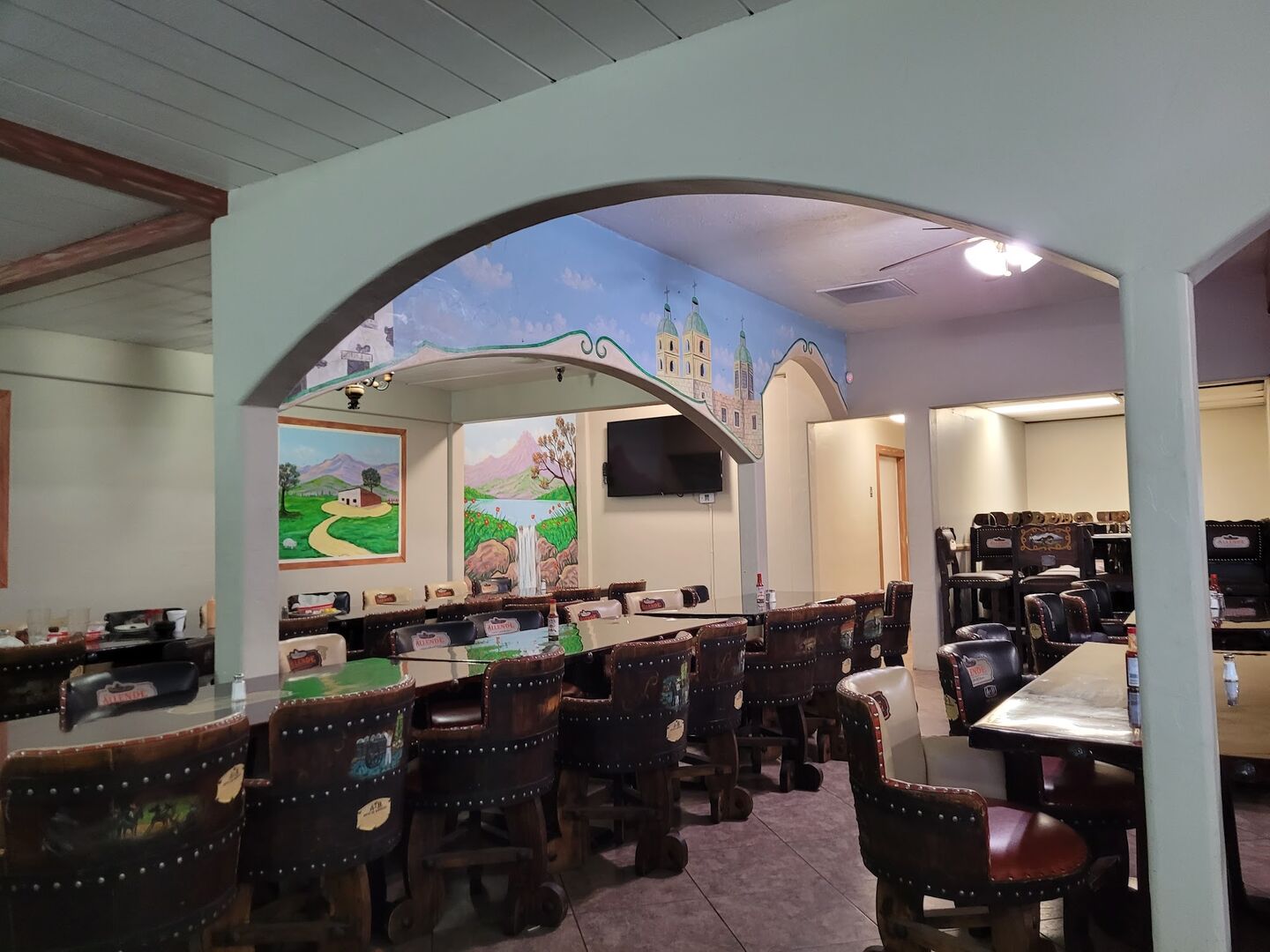 The dining room: arches, painted murals of hills and churches, rows of barrel chairs