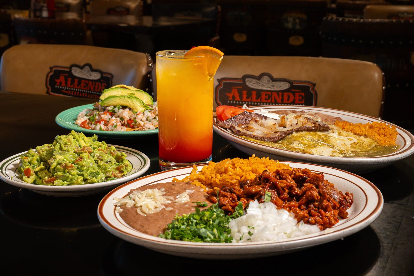A table at Allende: a sunrise-coloured drink, guacamole, a ceviche tostada with avocado, a carne asada plate and enchiladas