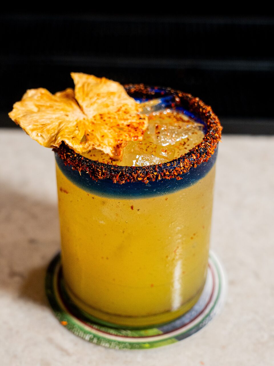 Una bebida de mango y piña escarchada con chile, con piña deshidratada de adorno